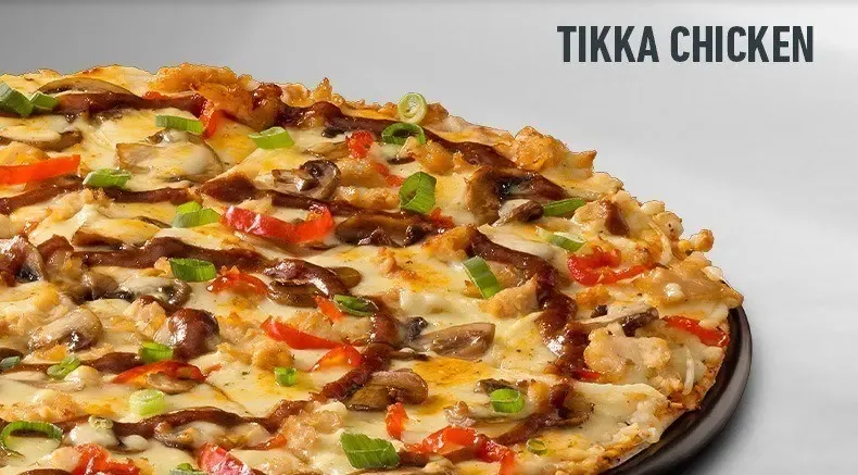 Large tikka chicken pizza on a black plate